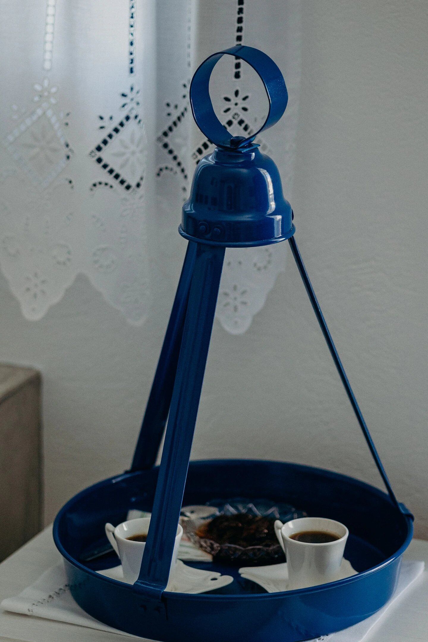 A blue hanging lamp with a white base and a circular shade, suspended from a ceiling hook.