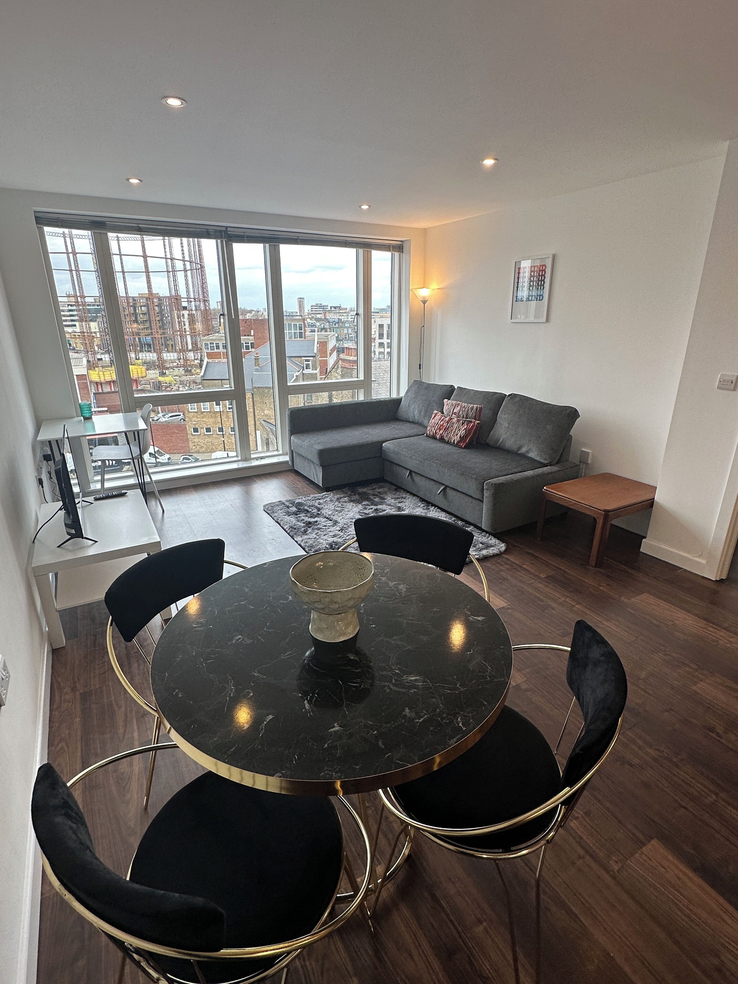 Una sala de estar moderna con comedor, ventanas amplias y vistas a la ciudad.