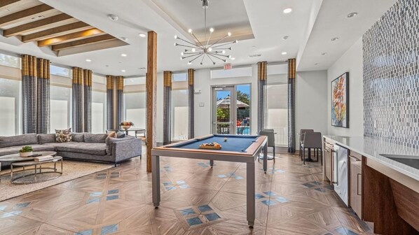 A modern hotel lobby with a pool table, a sofa, and a dining area.