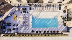 An aerial view of a rooftop pool area with lounge chairs, a pool, and a sun terrace. - Landing | Incredible 1BD, Courtyard, Gym (Kansas City)