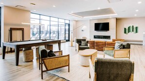 A modern living room with a pool table, comfortable seating, a flat-screen TV, and a fireplace. - Landing | Stunning 1BD, Yoga Studio, Courtyard (Kansas City)