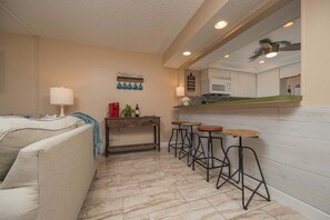 A compact living space with a kitchenette, a dining area with bar stools, and a sofa. - Pelican Inlet D229- The Chubby Mermaid (St. Augustine)