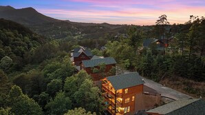 Eine Lodge mit mehreren Holzhütten, umgeben von dichtem Wald, mit Balkonen und einem malerischen Bergpanorama.