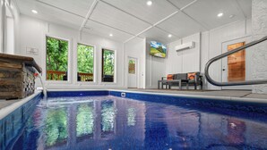 Ein Hallenbad mit großen Fenstern, einer Holzbank und einer Treppe.