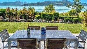 Une table à manger avec des chaises, installée à l’extérieur, offrant une vue panoramique sur un lac et des montagnes.