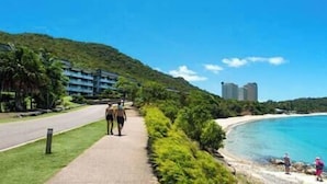 Une promenade en bord de mer, avec une plage et un hôtel en arrière-plan.
