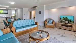 Un salon moderne avec un canapé, des fauteuils, une table basse et un téléviseur.