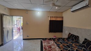 A hotel room with a bed, a ceiling fan, an air conditioner, and a view of the outside. - Gir Forever  (Talala)
