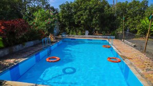 A rectangular swimming pool with clear blue water, surrounded by a tiled deck and a metal fence. - Gir Forever  (Talala)