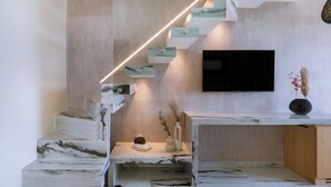 Una escalera moderna con escalones de mármol y un televisor instalado en la pared.