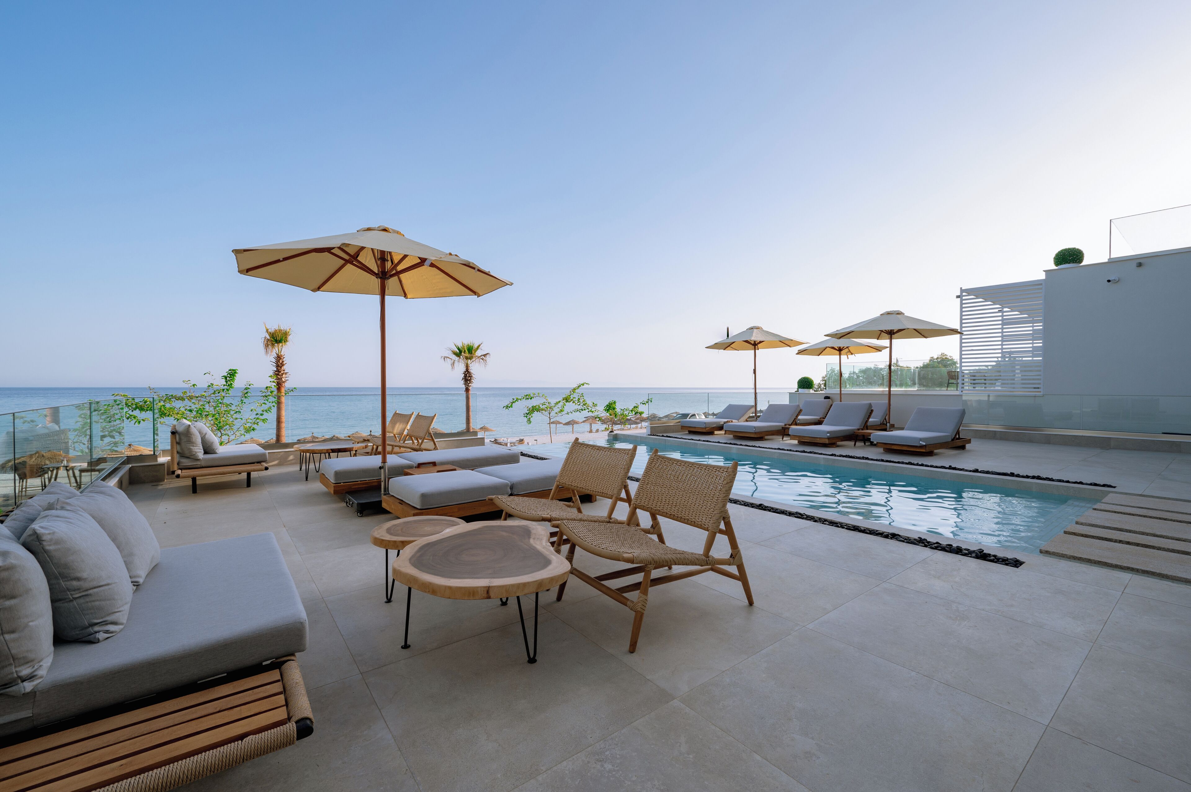 Zona de piscina en la azotea con sillones, sombrillas y vista al océano.