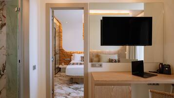 A hotel room with a bed, a desk with a laptop, a television, and a telephone.