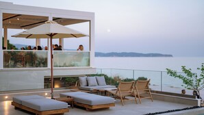 Un área de descanso moderna al aire libre, con asientos y piscina, con vistas a una costa pintoresca.