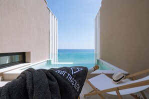 A balcony with a view of the ocean, a towel with 'ZEST THASSOS' text, and a hat on a chair. - ZEST THASSOS LUXURY RETREAT (Thasos)