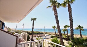 Un balcon avec vue sur la plage, les palmiers et la mer.