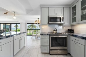 Une cuisine moderne avec des meubles gris, un four en acier inoxydable, un four à micro-ondes et un grille-pain.