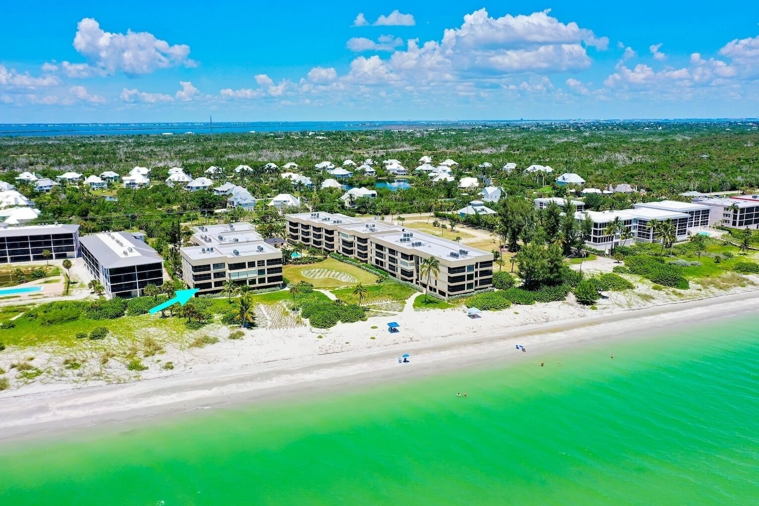 A coastal resort with multiple buildings, a beach, and a clear view of the ocean.