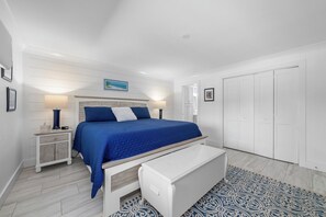 A bedroom with a bed, bedside tables, a bench, and a patterned rug.