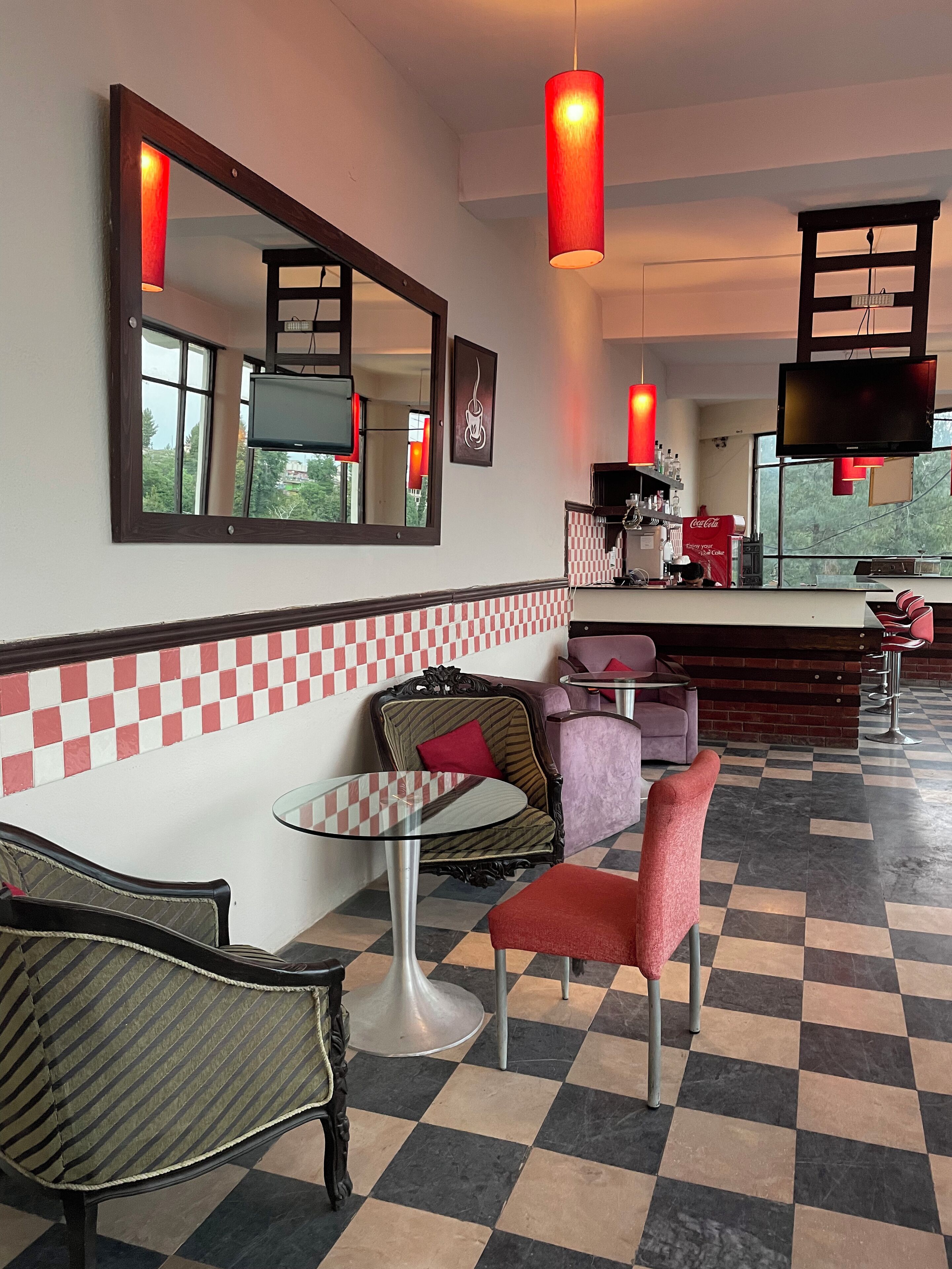 A hotel lobby with checkered flooring, a bar area, and seating arrangements including a table and chairs.