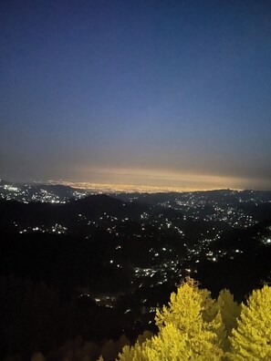 Un paisaje urbano nocturno con luces de ciudad a lo lejos y un cielo despejado.