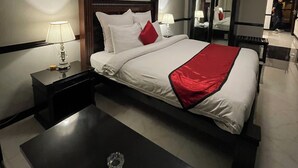 Una habitación de hotel con cama, mesitas de noche, un escritorio y un espejo.