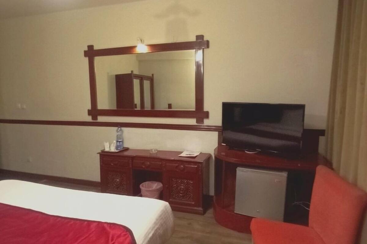 A hotel room with a bed, a TV, a desk, and a chair.