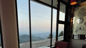 Una habitación con ventanas amplias, una mesa redonda y sillas rojas.