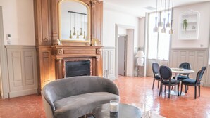 Ein Wohnzimmer mit Kamin, einer Couch, einem runden Couchtisch und einem Essbereich mit Stühlen und Tisch.