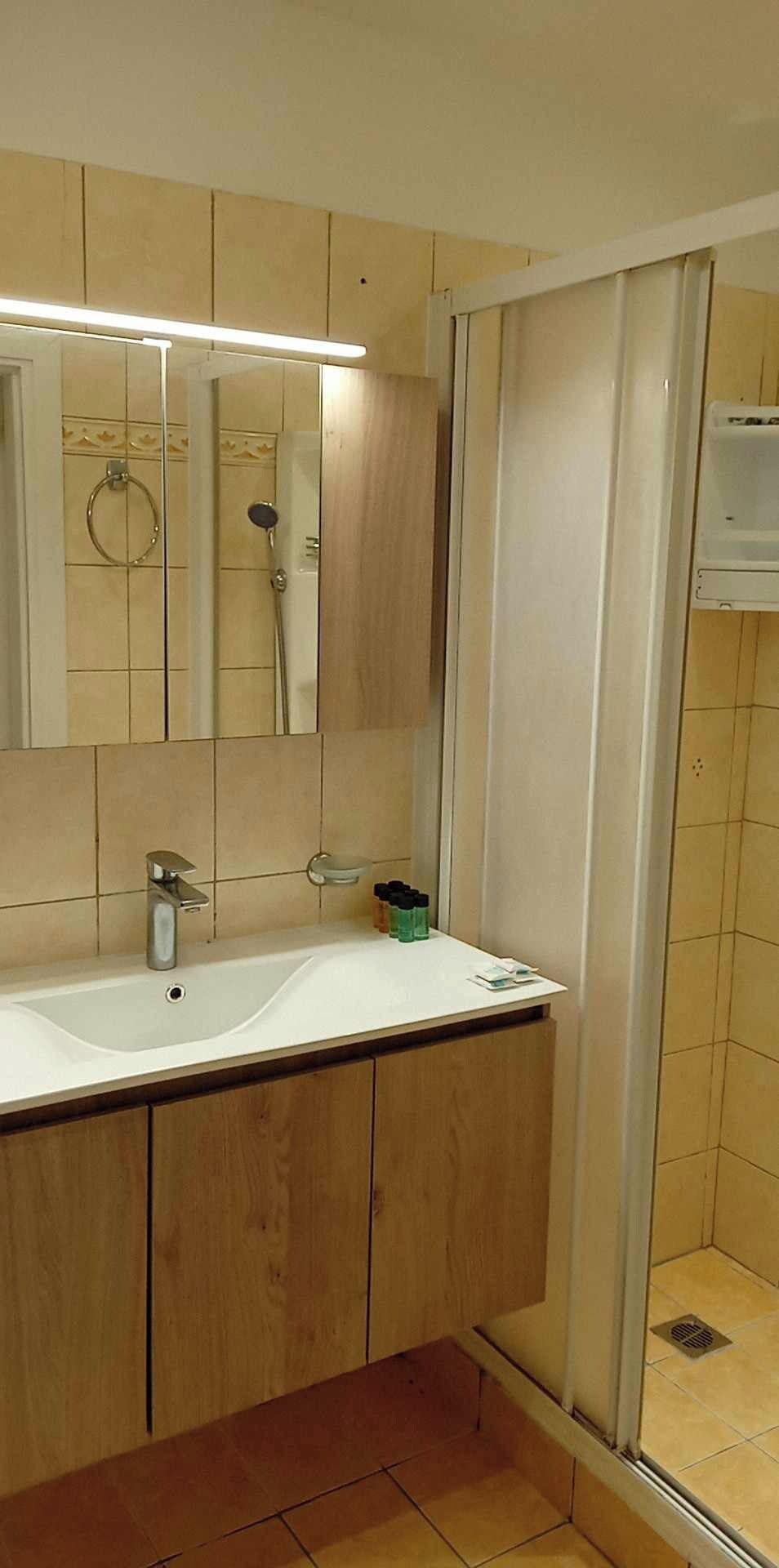 Un bany amb un lavabo doble, armaris de fusta, un mirall i una dutxera.