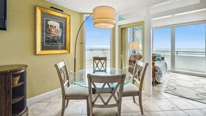 A dining area with a glass table and chairs, a framed picture on the wall, and a view of the balcony. - Includes Xplorie Activities and Linens. PYRAMID - 1BR Veranda condo w/outdoor pool. (Ocean City)