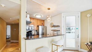 A modern kitchen with a marble countertop, stainless steel appliances, and a glass door leading to a balcony. - Includes Xplorie Activities and Linens. PYRAMID - 1BR Veranda condo w/outdoor pool. (Ocean City)