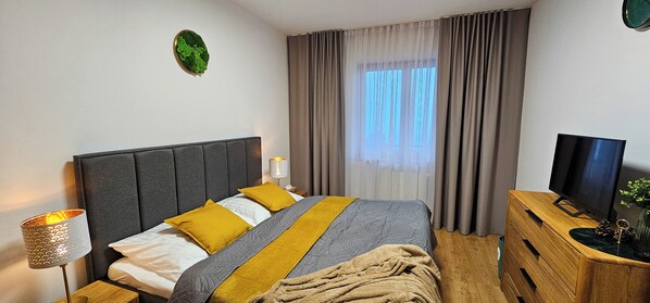 A neatly arranged bedroom with a bed, bedside lamp, TV, and a dresser.