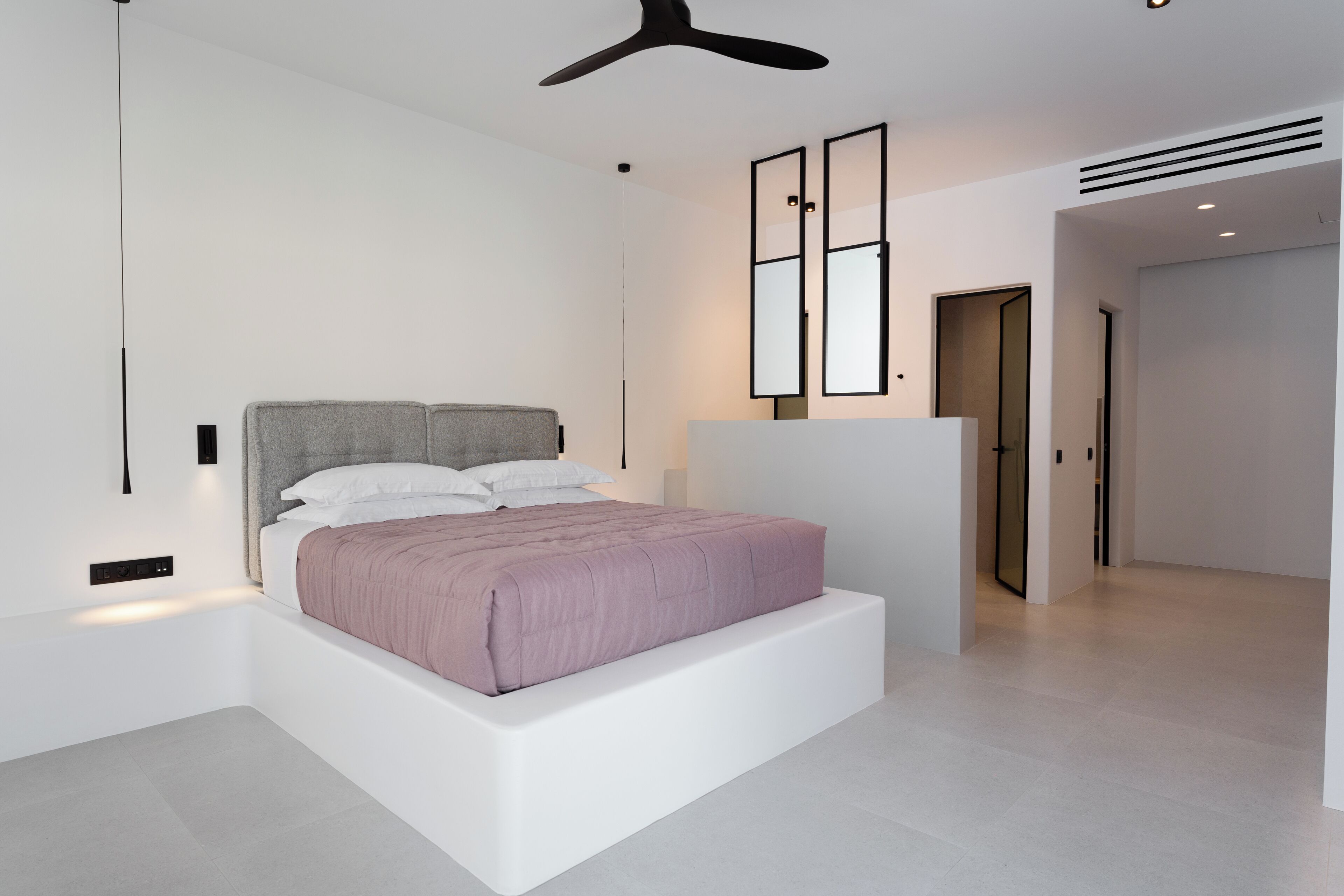 Un dormitorio moderno con una cama grande, un ventilador de techo y un diseño minimalista.