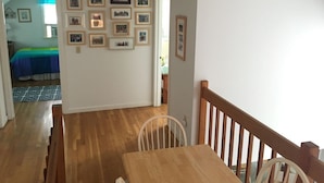 Un comedor con una mesa y sillas de madera, una escalera y una pared decorada con cuadros.