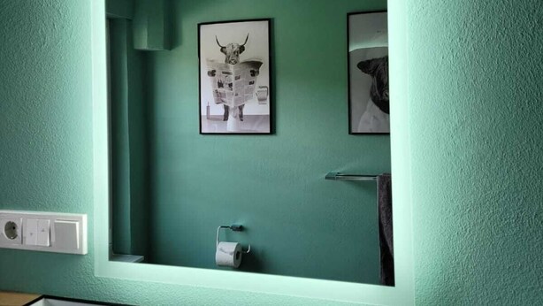A bathroom with a green wall, a framed picture of a bull, and a towel rack. - Haus Valentonio Einz (Zeltingen-Rachtig)
