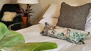 Un lit bien fait, agrémenté d’un coussin à motifs zébrés, d’une lampe et d’une chaise avec un coussin moelleux.