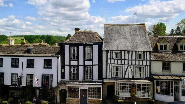 Une rangée de bâtiments traditionnels à colombages, avec un ciel bleu clair et des nuages en arrière-plan.