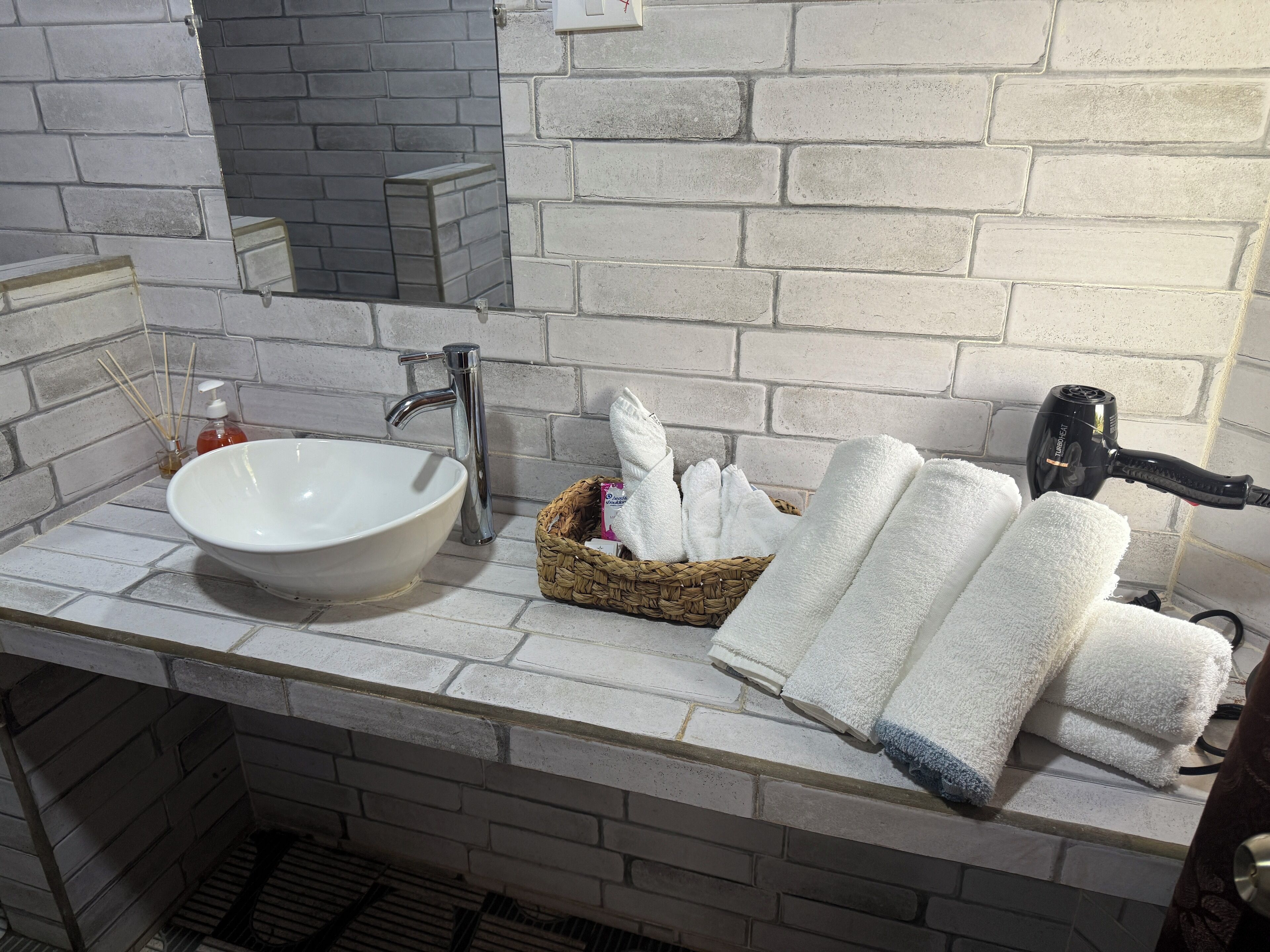 A bathroom with a white sink, a mirror, a towel rack, and a basket of towels.