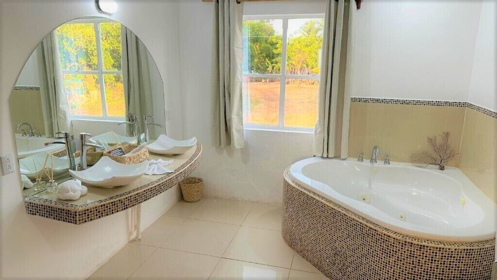 A bathroom with two sinks, a large bathtub, and a mirror.