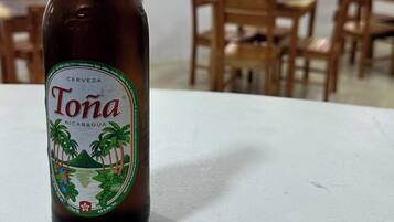 Een fles Tona bier op een tafel in een kamer met houten stoelen en tafels.