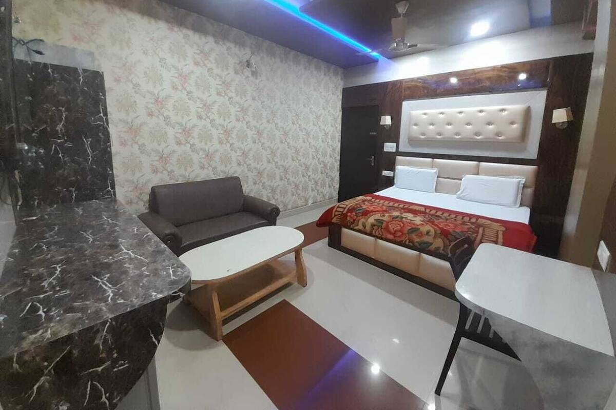 Una habitación de hotel con cama, sofá, una mesita y encimera de mármol.