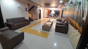 A spacious lobby with a central seating area, a staircase, and a decorative wall mural. - Shri Sai Palace (Mau Ranipur)