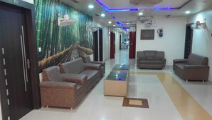 A modern lobby with a sofa set, a coffee table, and a chandelier. - Shri Sai Palace (Mau Ranipur)