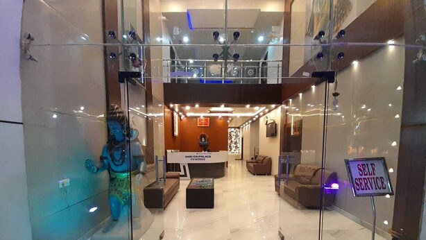 A hotel lobby with a reception desk, seating area, and a 'Self Service' sign. - Shri Sai Palace (Mau Ranipur)