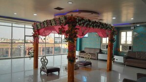 A spacious lobby with a decorative floral canopy, seating areas, and large windows offering a view. - Shri Sai Palace (Mau Ranipur)
