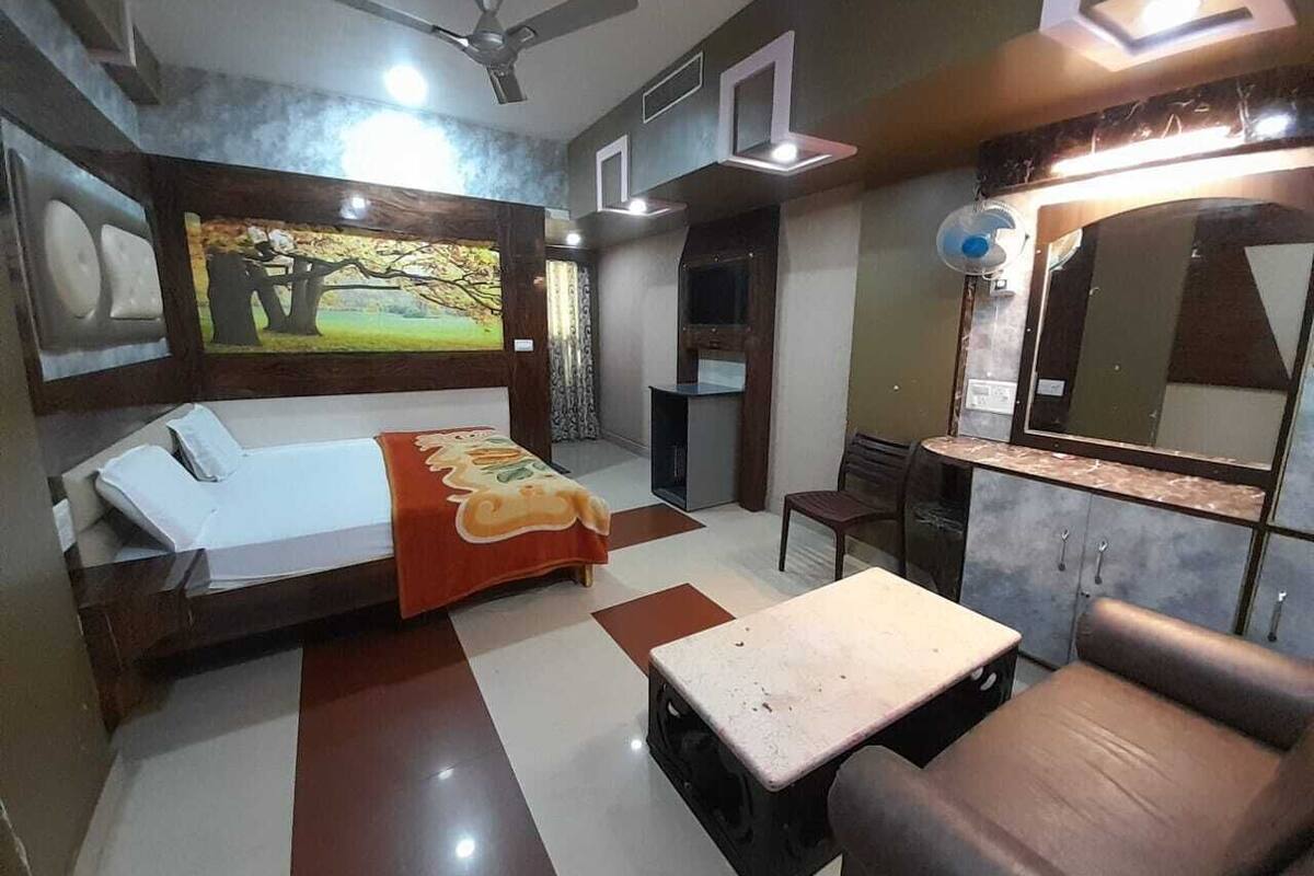 Un dormitorio con cama, escritorio, silla, espejo y ventilador de techo.