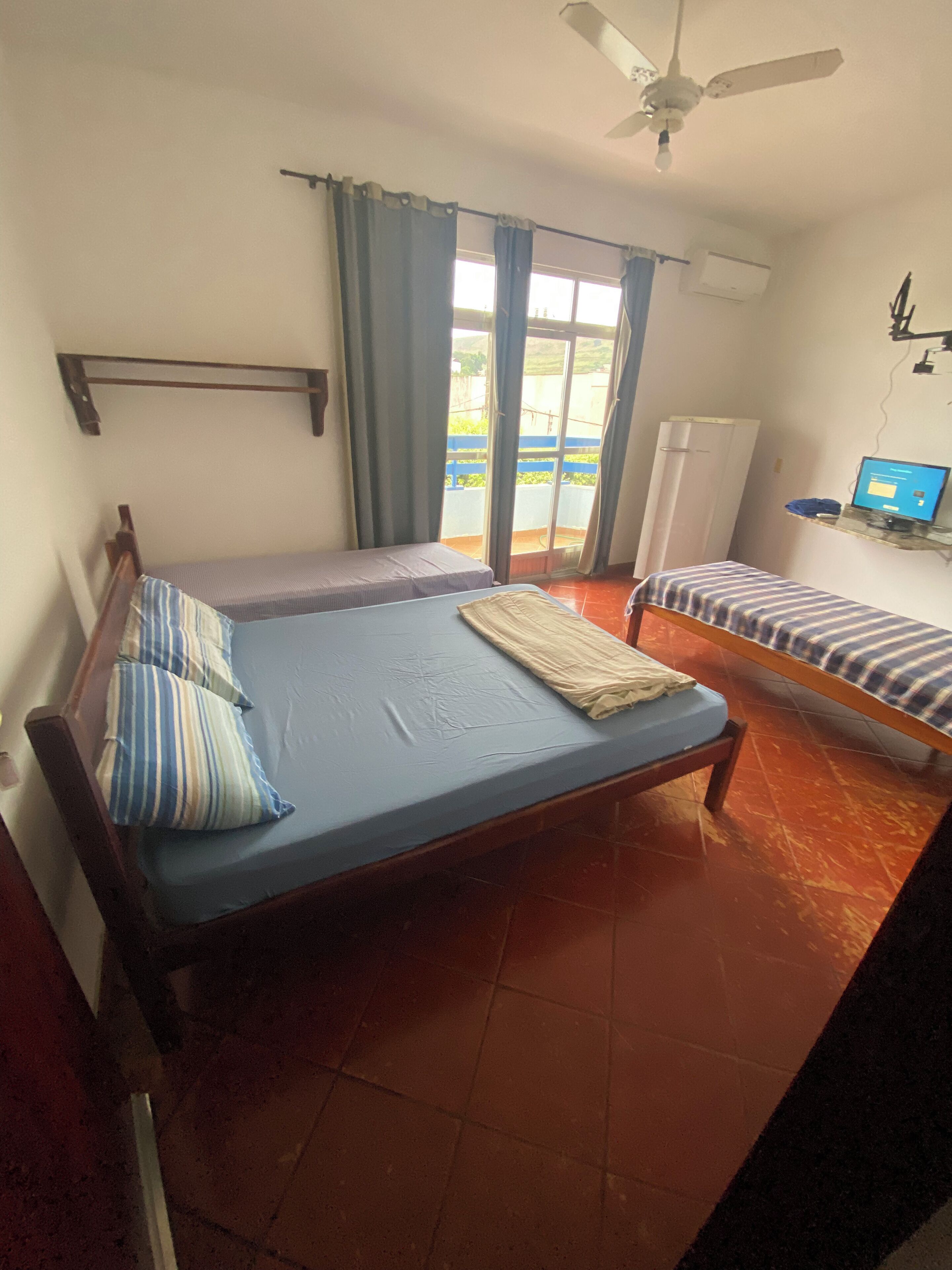 A bedroom with a bed, a small table, a ceiling fan, and a window with curtains.