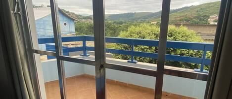 A room with a large window overlooking a balcony with a blue railing.