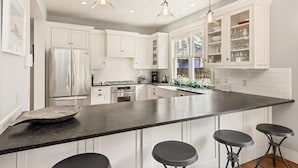 A modern kitchen with white cabinetry, a large island with bar stools, and pendant lighting. - Family-Friendly East Aspen Retreat with Hot Tub, Views & Minutes to Downtown (Aspen)