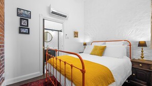 A bedroom with a bed, a nightstand, a lamp, and a red and black patterned rug. - Arapiles Crash Pad in Natimuk (Natimuk)